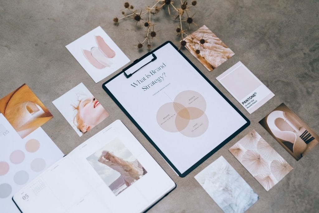 Mood board on concrete with "What is Brand Strategy?" clipboard, Pantone swatches, and aesthetic lifestyle photographs.