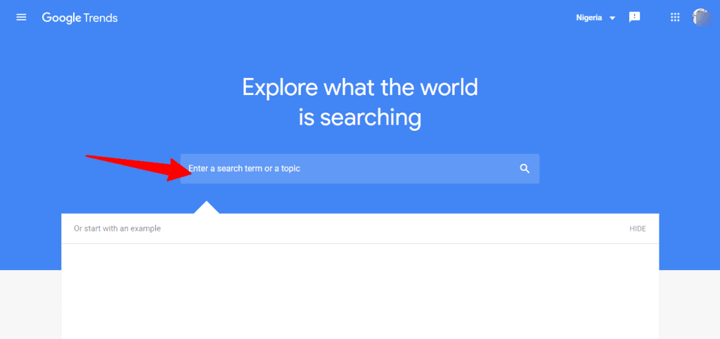 Google Trends homepage with blue background and a search bar indicated by a red arrow.