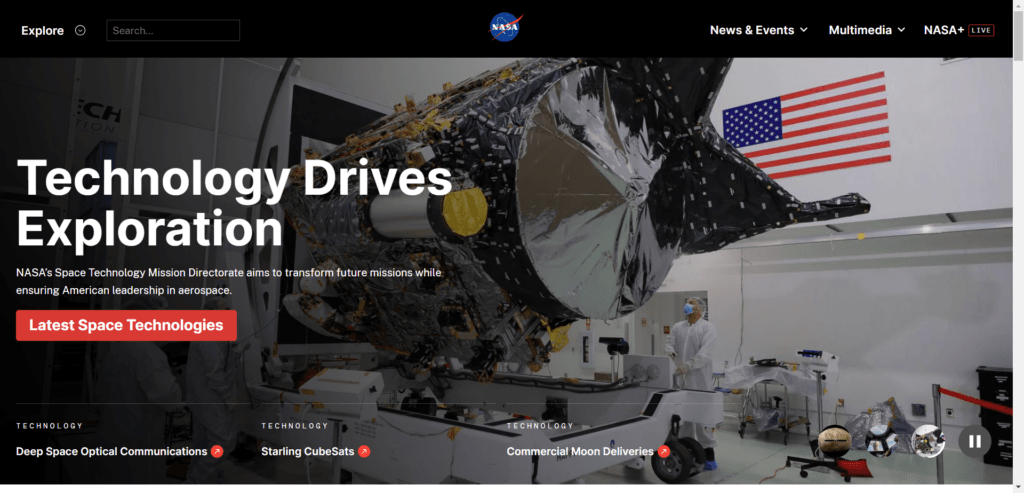 A screenshot of the official NASA website featuring the headline "Technology Drives Exploration." The background shows a large piece of space hardware being worked on by technicians in a cleanroom environment, with an American flag visible on the wall. The interface includes a search bar, a "Latest Space Technologies" red button, and navigation links for News & Events, Multimedia, and NASA+ Live. Lower sections highlight specific projects like Deep Space Optical Communications, Starling CubeSats, and Commercial Moon Deliveries.